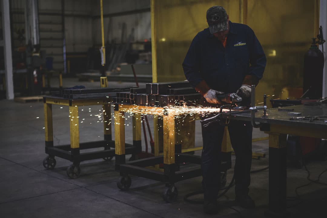 A fabricator grinding custom metal architectural components