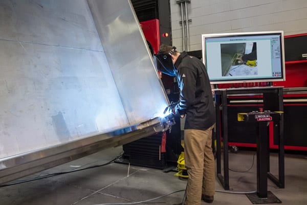 A welder using an automated positioning system to weld a large metal container for the oil and gas industry