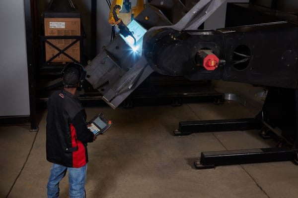 A robotic welder welding a metal component for the oil and gas industry