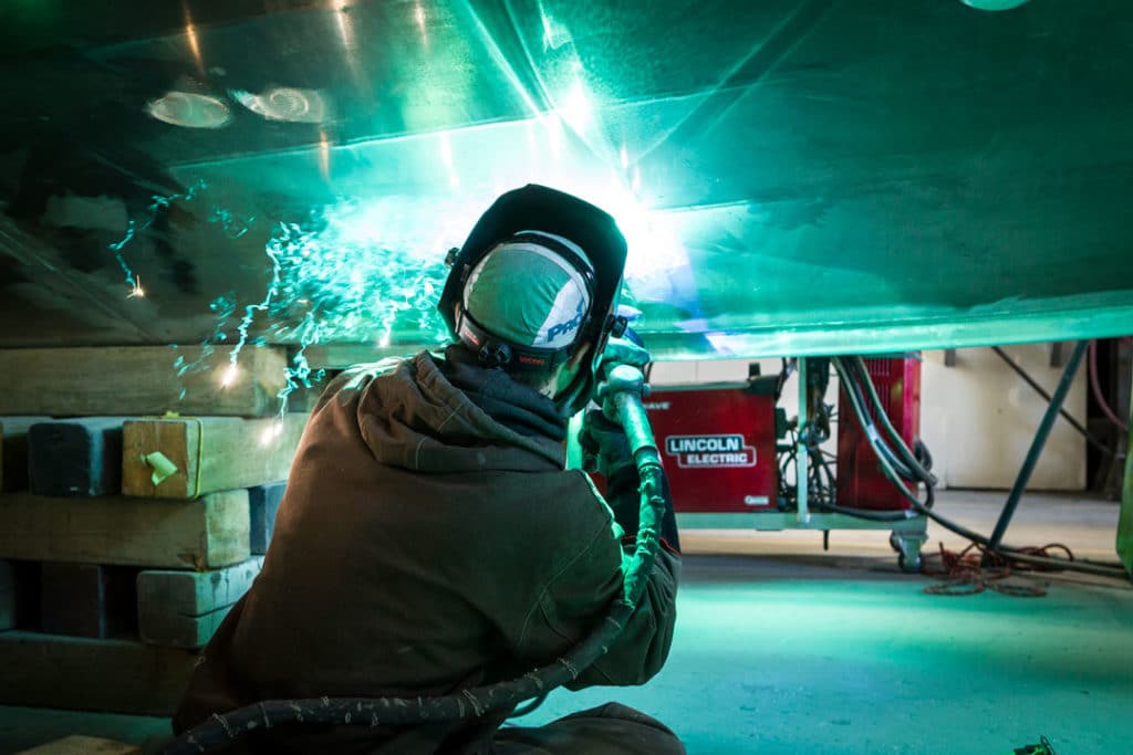 A fabricator MIG (GMAW) welding a large metal part for the shipbuilding industry