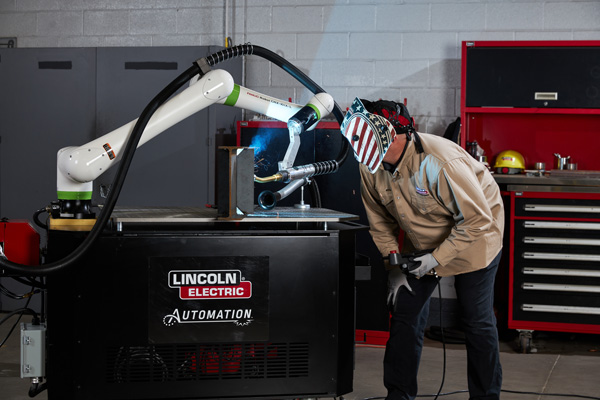 An automation technician watching a collaborative robotic welder