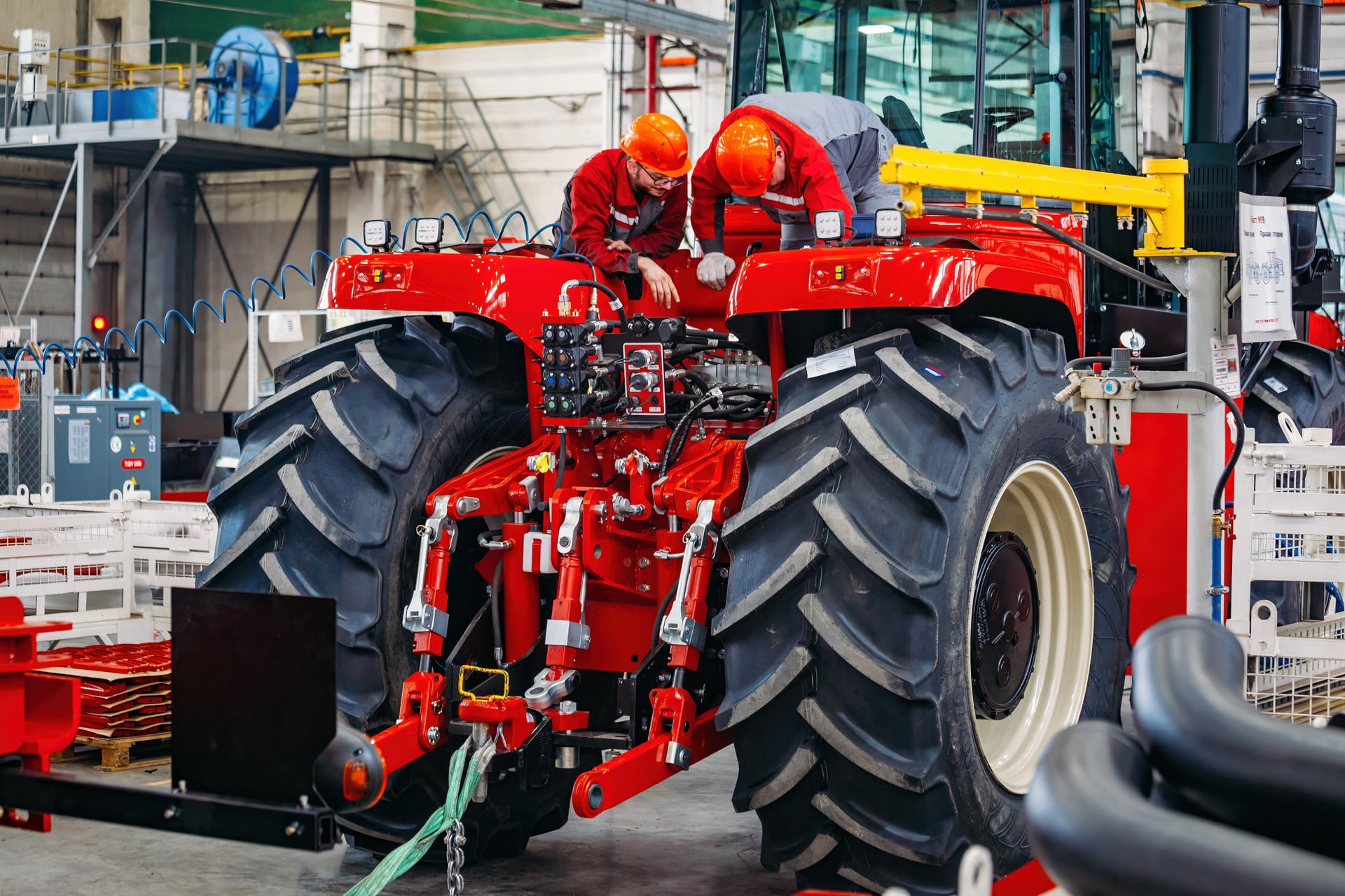 Workers install precision-fabricated components on a tractor in a factory